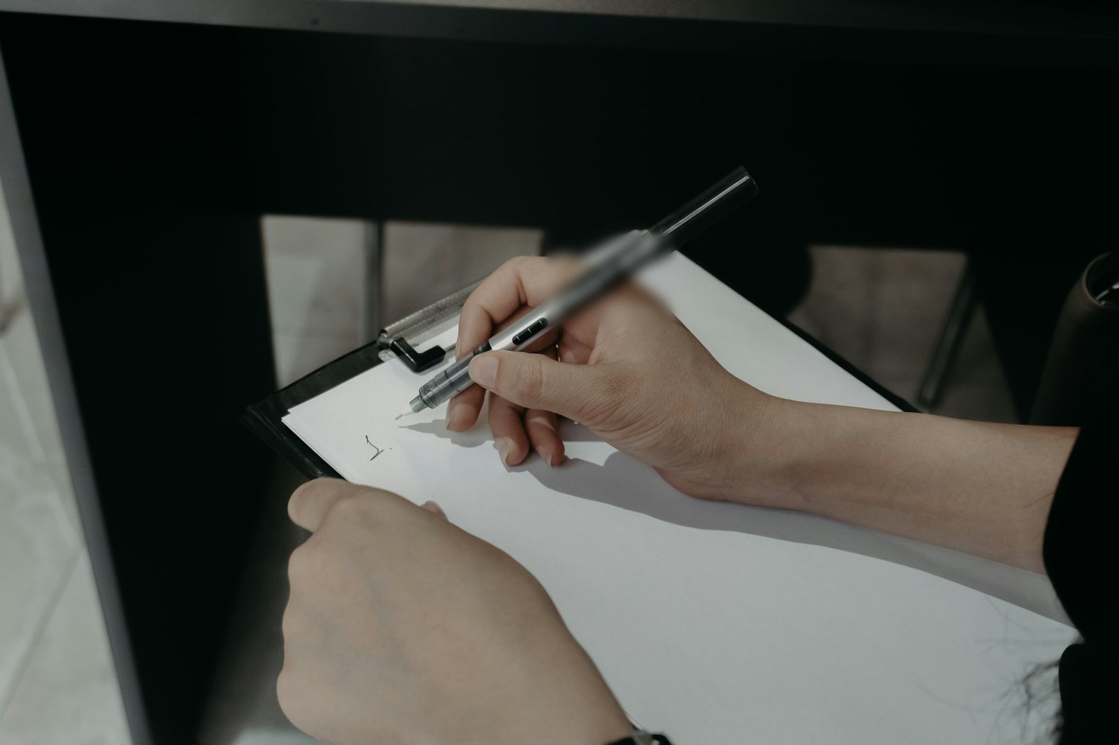 Hands writing on a clipboard in front of storage shelving