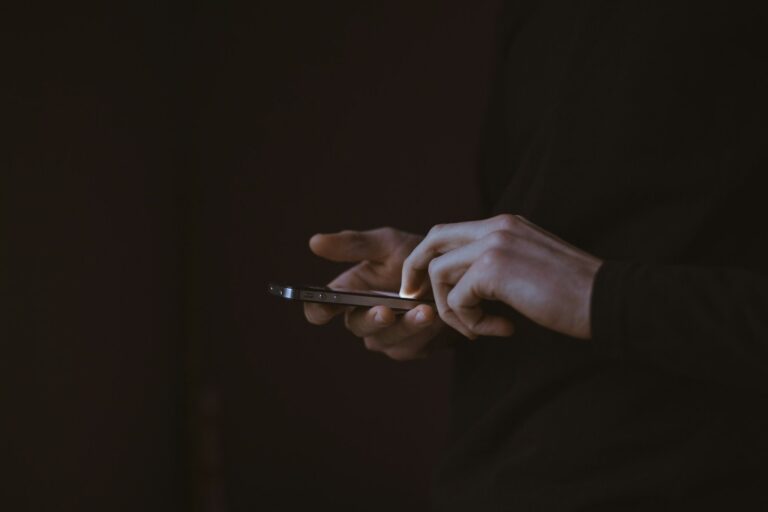 Hands holding a phone against a dark background